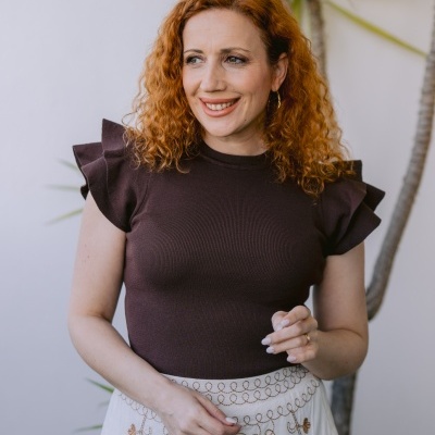 Mulher com t-shirt castanha e saia branca bordada com padrões florais