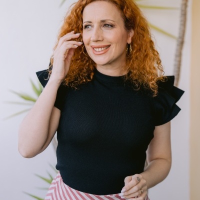 Mulher ruiva de blusa preta e saia riscada diagonais vermelhas e brancas