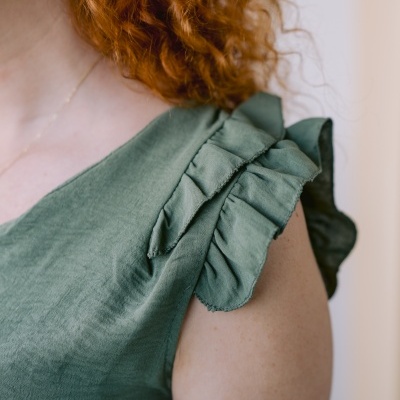 Blusa verde com folhos nas alças vista no ombro e braço