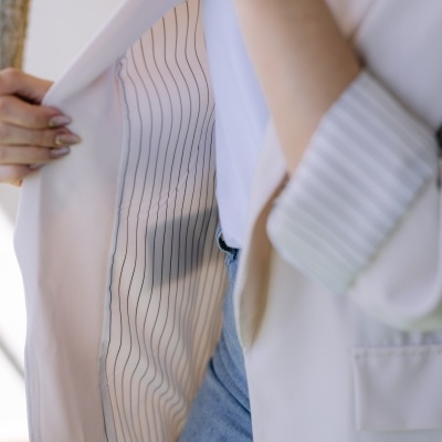 Casaco branco com forro riscado mostrado por mulher com jeans azuis e t-shirt branca