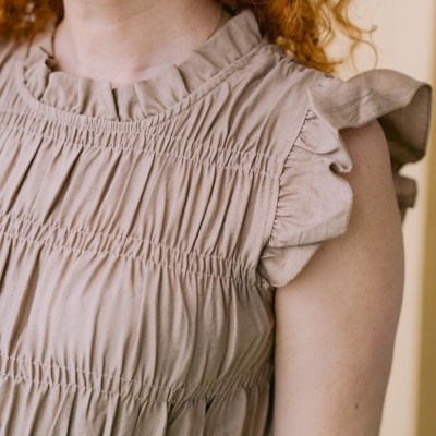 Blusa bege com folhos e franjas na zona do peito e ombros