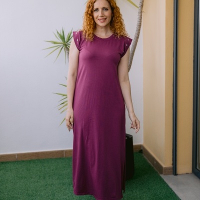 Mulher com vestido longo bordeaux sem mangas e ilhóses nos ombros