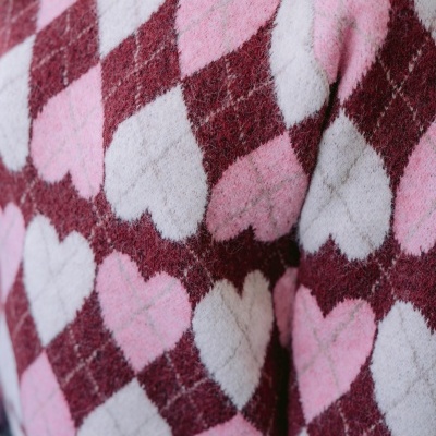 Suéter de malha com padrão argyle rosa, branco e borgonha com corações.