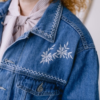 Casaco de ganga azul com bordado branco floral e costuras zig-zag