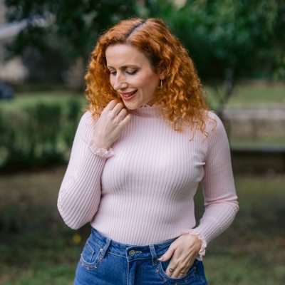 Mulher com camisola rosa e jeans azuis em ambiente exterior