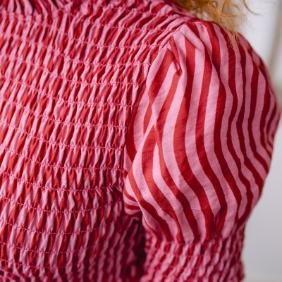 Blusa vermelha e rosa com franzidos na gola e tecido franzido no peito