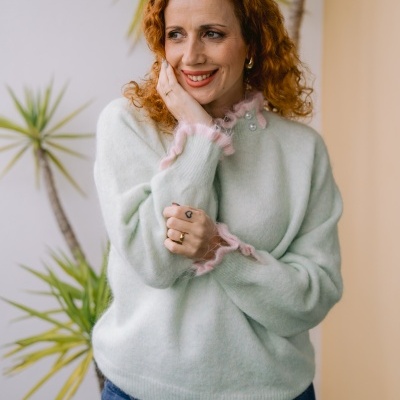 Mulher com camisola verde-água com detalhes rosa e calças de ganga azuis