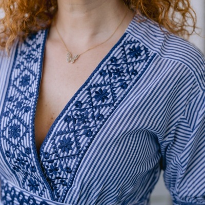 Blusa azul listrada com bordados florais e geométricos no decote e cintura
