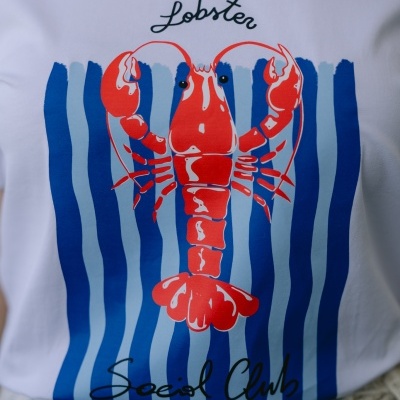 T-shirt branca com estampa frontal de lagosta vermelha e riscas azuis.