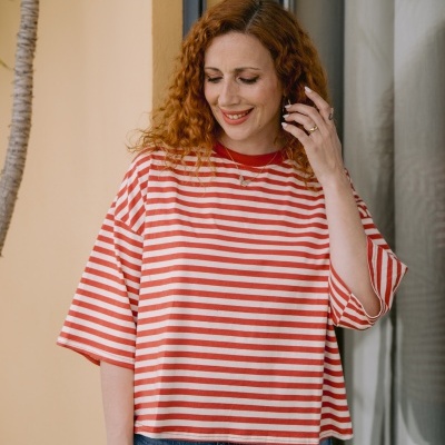 T-shirt de riscas brancas e vermelhas com jeans azul em modelo feminino.