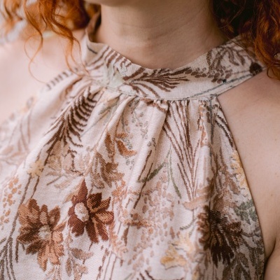 Blusa feminina de tecido floral com gola alta usada por mulher com cabelo ruivo