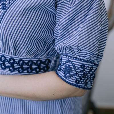 Riscas azuis e brancas com bordados azuis escuros numa manga e cintura de roupa