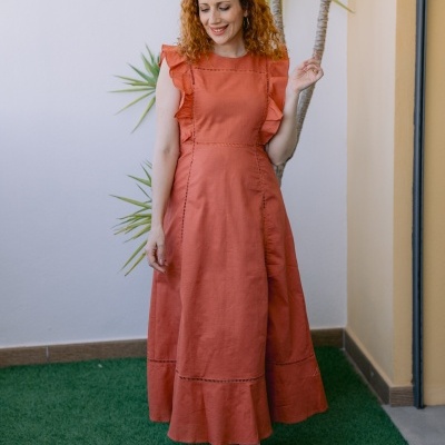 Vestido midi terracota com babados e sandálias douradas num jardim