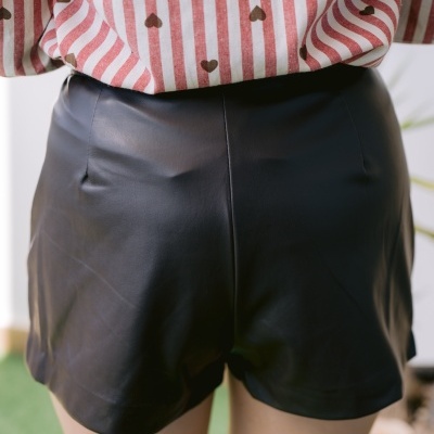 Calções curtos pretos de tecido efeito pele e camisa branca riscada com corações castanhos