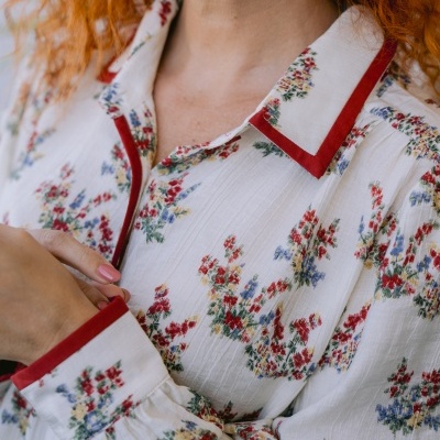 Blusa feminina branca com flores coloridas e bordas vermelhas no colarinho e punhos