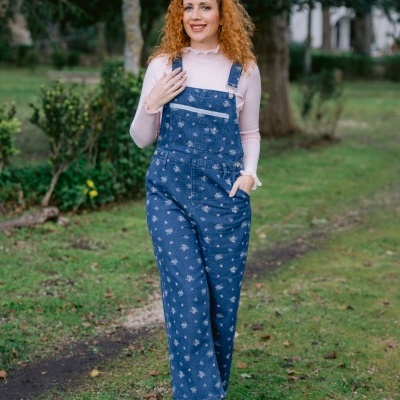 Mulher com macacão de ganga azul com flores e camisola rosa num parque