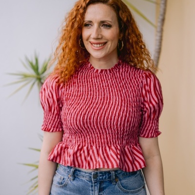 Mulher com blusa rosa de riscas verticais e calças de ganga em ambiente com plantas