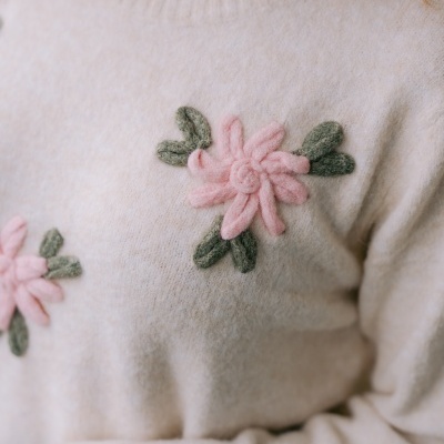 Camisola bege de malha com flores cor-de-rosa e folhas verdes em relevo