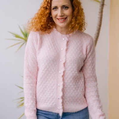 Mulher de cabelo ruivo com casaco rosa claro e calças de ganga azuis