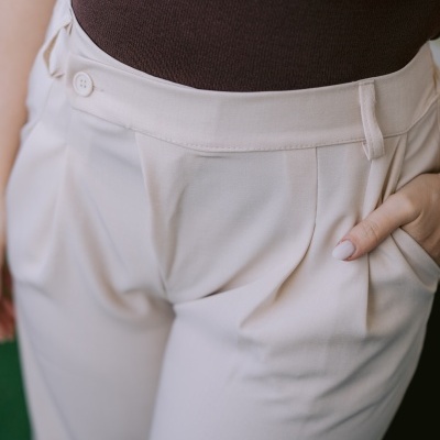 Calças bege claro com botão e bolso, combinadas com camisa malha castanha