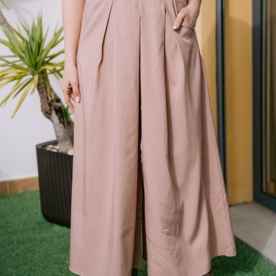 Calças largas bege com pregas frontais e botas castanhas em ambiente exterior