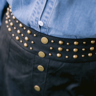 Saia preta com botões e tachas douradas e camisa de ganga azul clara