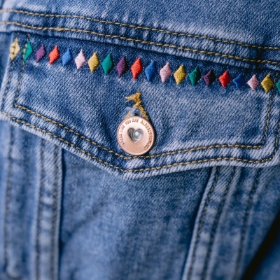 Bolso de ganga azul claro com bordado colorido e botão com texto