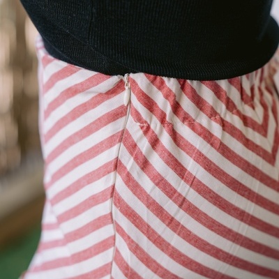 Detalhe lateral de saia às riscas vermelhas e brancas com fecho invisível e top preto canelado