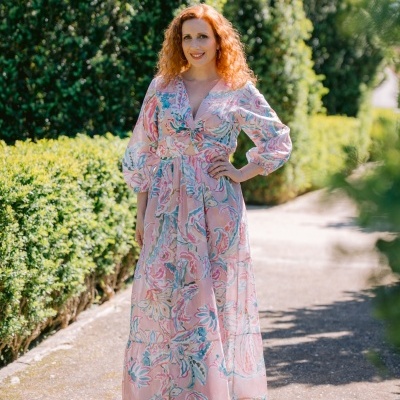 Mulher com vestido rosa floral comprido ao ar livre.