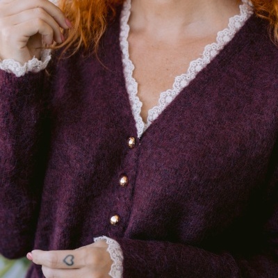 Cardigã roxo com renda branca e botões dourados em modelo feminino