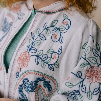 Casaco branco bordado com motivos florais em azul, verde e rosa