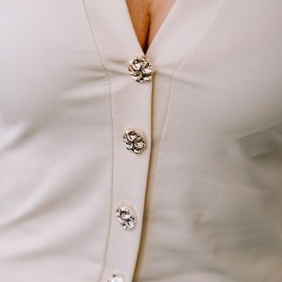 Top feminino bege com botões florais metálicos