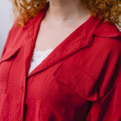 Camisa vermelha com bolsos e gola clássica em pessoa com cabelo ruivo e brincos dourados