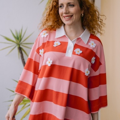 Mulher com camisa polo às riscas vermelha e cor-de-rosa com flores.