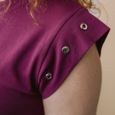 Peça de roupa roxa com botões metálicos no ombro