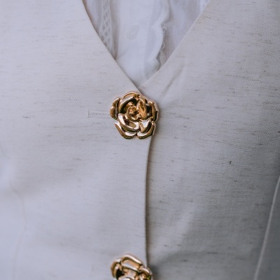 Casaco branco com botões dourados em forma de flor e camisa branca por baixo