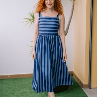 Vestido midi azul às riscas usado por mulher com cabelo ruivo