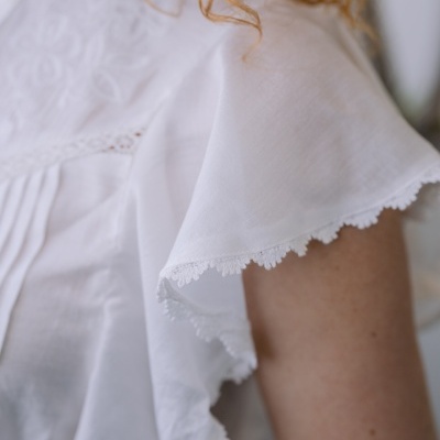 Parte superior branca de mulher com bordado floral e renda nas mangas