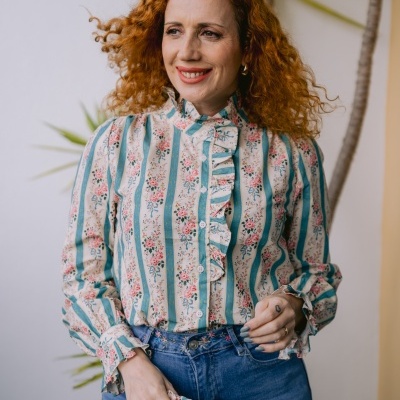 Camisa feminina com padrão floral e listras verdes, botões e folhos, usada com jeans azul.