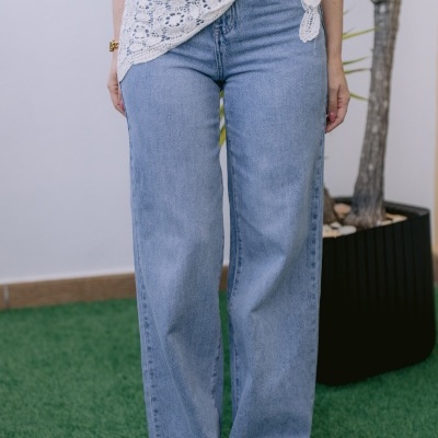 Calças de ganga azul claro de corte largo com blusa branca estampada e cinto de renda branco na cintura