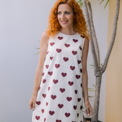 Vestido branco curto com corações vermelhos usado por mulher de cabelo ruivo encaracolado