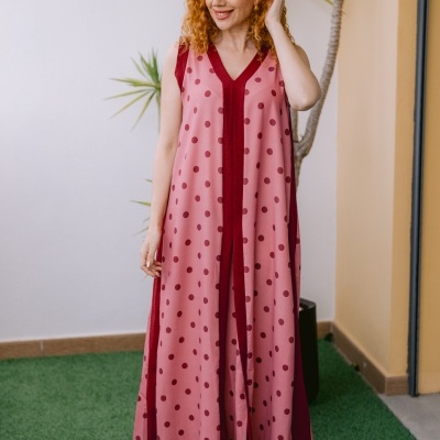 Vestido longo rosa com bolinhas vermelhas usado por mulher com cabelo ruivo