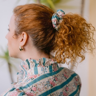 Mulher ruiva com scrunchie azul floral e blusa riscada com flores