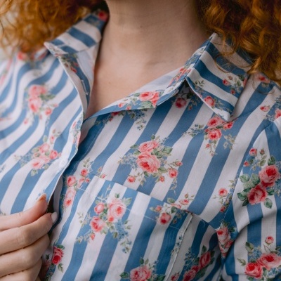 Camisa de riscas azuis e brancas com flores vermelhas e rosa e bolso frontal