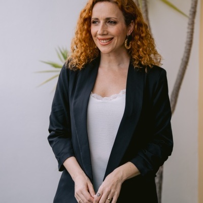 Mulher com blazer preto e top branco em ambiente com planta