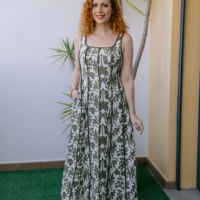 Vestido comprido com padrão de folhas verdes e fundo bege usado por mulher ao ar livre