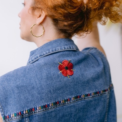 Colete de ganga azul com bordado de flor vermelha e detalhes coloridos