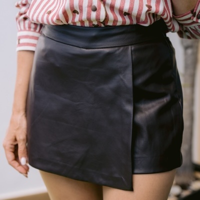 Saia preta curta de couro e blusa riscada com corações e botões
