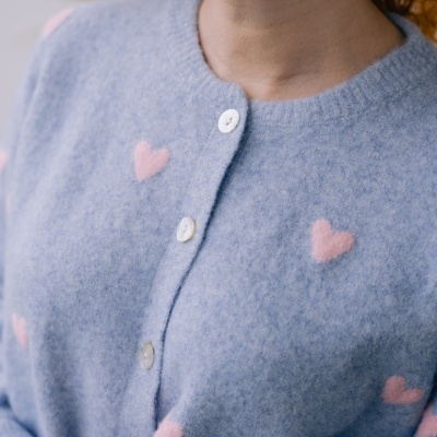 Cardigã azul claro com corações cor-de-rosa e botões brancos