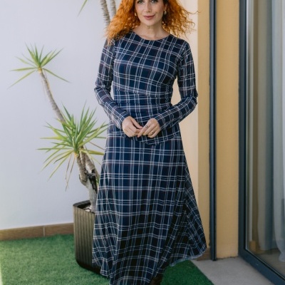 Vestido comprido xadrez azul com manga comprida usado por mulher de cabelo ruivo.